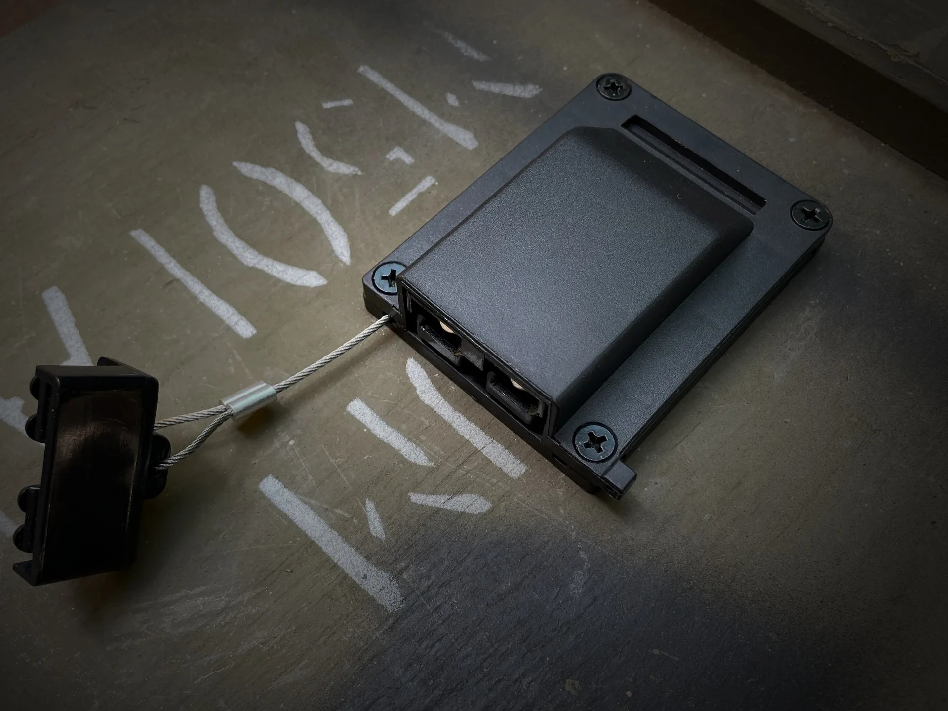 The WRAITH housing, showing the connector, four corner screws, the riser base and the dust cap on its tether