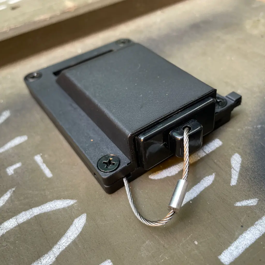 The WRAITH housing mounted to a panel, viewed from the back, wire rope exiting through the rear channel