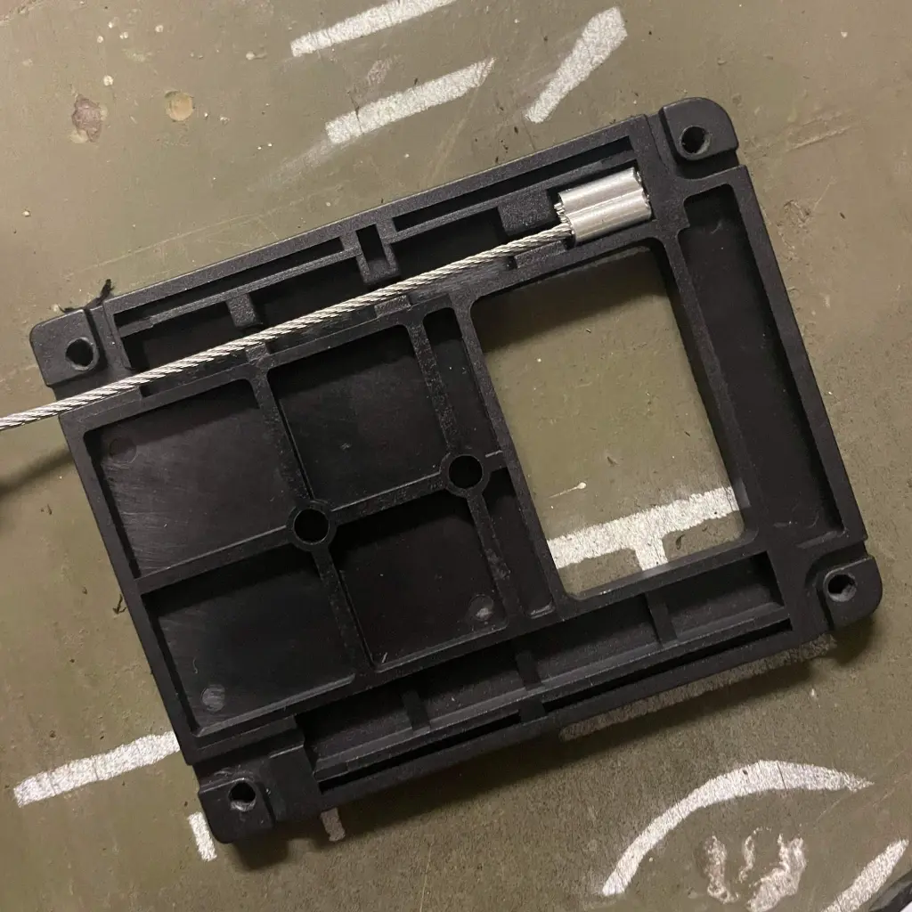 The underside of the WRAITH riser base, showing the wire rope channel and screw holes